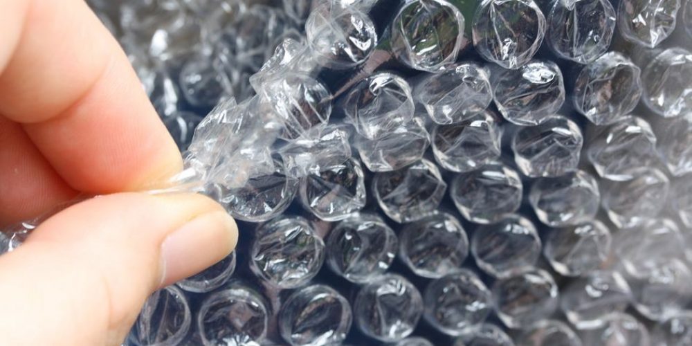 A man is popping bubble wrap used to wrap parcel from China to Malaysia.